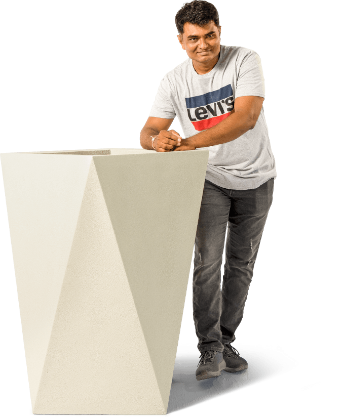 a man in grey t-shirt leaning against a grey coloured big planter